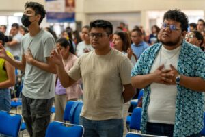 A diverse group of people engaged in prayer at a religious service in Ciudad de México.