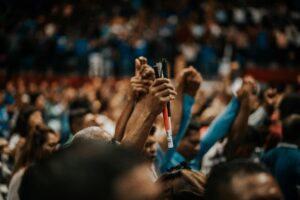 Energetic crowd with raised hands in a vibrant indoor gathering, symbolizing unity.